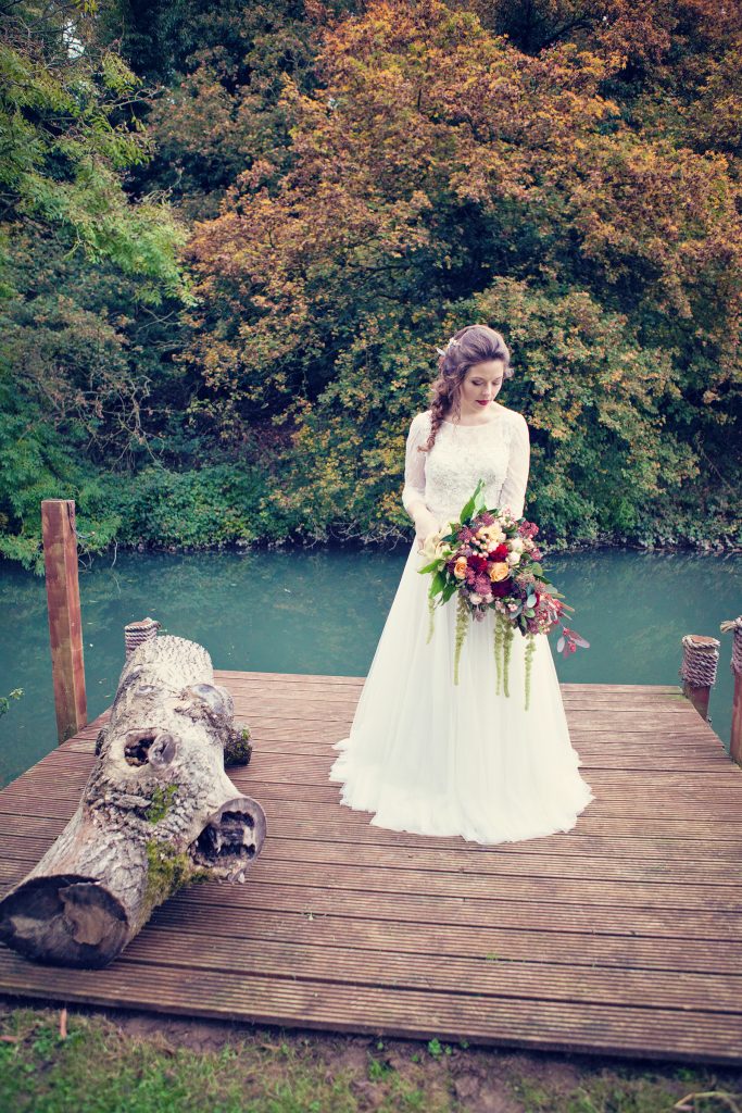 Bride with bouquet by river | Mae Bridal | Classic Flowers | Wind in the Willows | marsala & gold | autumnal | Old Swan & Minster Mill | Witney | October 2016 | Photography by Farrow Photography www.farrowphotography.co.uk