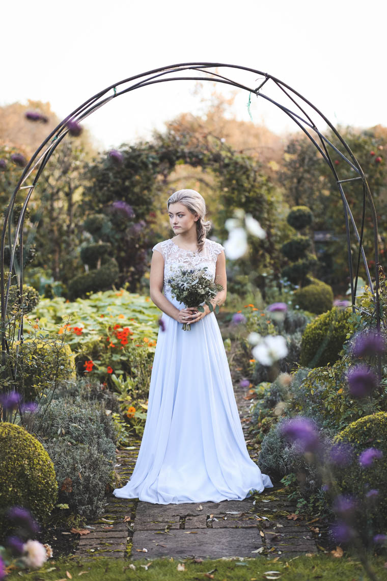 Bridesmaid under arch in garden | Journey to the Centre of the Earth | modern ethereal winter styled bridal shoot by Hanami Dream | agate | marble | airplants | tulle | pale blue | gold | Oxleaze Barn | Gloucestershire | October 2017 | Photography by Squib Photography www.squibphotography.co.uk